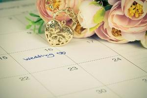 word wedding on calendar and gold bracelet with heart photo