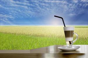 Cool Late coffee in hight glass on table with Rice field landscape. photo