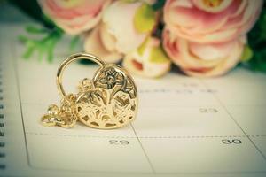 word wedding on calendar and gold bracelet with heart photo