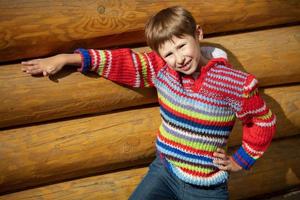 un chico de elemental años en un a rayas suéter en un antecedentes de un de madera cerca. foto