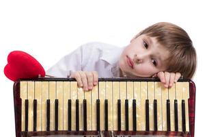 niño con un musical instrumento. elemental años chico con un acordeón. foto