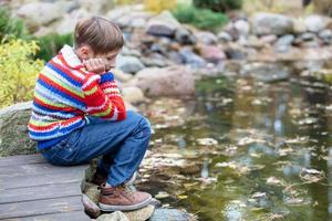 niño en un otoño caminar. triste chico por el lago. foto