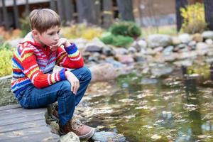 niño en un otoño caminar. triste chico por el lago. foto