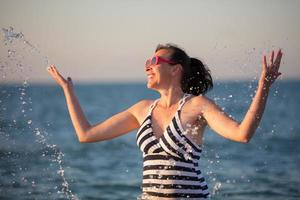 A beautiful old woman at sea. A beautiful middle-aged woman splashes sea water. photo