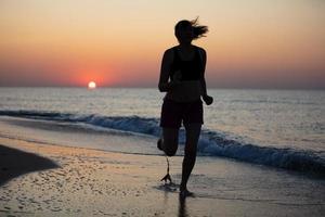 silueta de un mujer atleta en un antecedentes de amanecer a mar foto