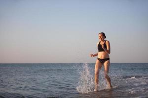 An elderly woman runs along the beach. photo