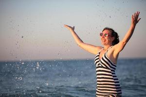 A beautiful old woman at sea. A beautiful middle-aged woman splashes sea water. photo