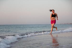 un de edad mediana mujer trotar a lo largo el costa. Deportes a mar adulto mujer. foto