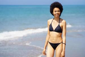 contenido negro mujer en bikini caminando en costa foto