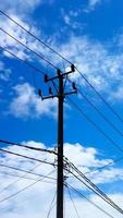 Electric pole in front of the house with bright clouds as a background. photo