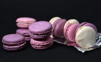 Macaroons on a shiny wrapper. Colorful delicious macaroons on a black background. Shiny cookie wrapper. photo