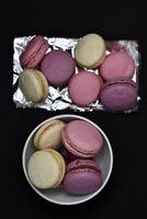 Macaroons on a shiny wrapper. Colorful delicious macaroons on a black background. Shiny cookie wrapper. photo