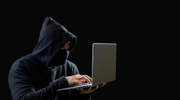 Hacker spy man one person in black hoodie sitting on a table looking computer laptop used login password attack security to circulate data digital in internet network system, night dark background. photo