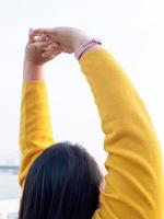 Portrait 30 year old fat Asian woman with long black hair wearing long sleeved yellow T-shirt. Standing with hands and arms raised stretch lazily body relax happily and freely on day off from her work photo