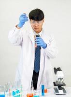 Asian man student scientist or doctor look hand holding in reagent mixing laboratory In a science research laboratory with test tubes of various sizes in  laboratory chemistry lab white background. photo