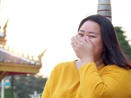 Portrait of an Asian woman, chubby, beautiful cute long black hair wearing black long sleeves, smiling. happily inside the park With happiness and peace of mind, relax during the evening time at sun photo