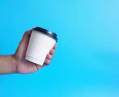 Man hand holding a white coffee cup, filled with hot black coffee americano, no sugar no milk, ready to drink, refreshing. aroma awake fresh to work placed on a blue isolated background photo