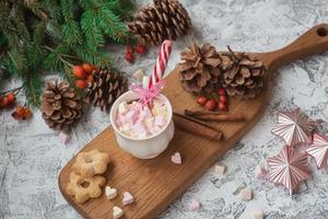 Copa de composición de año nuevo o navidad con marshmelow sobre un soporte de madera con galletas y dulces entre ramas de abeto verde foto
