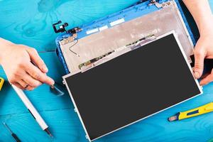 Wizard repairs laptop with tools and hands on the blue wooding table. top view photo