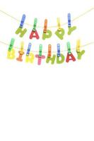 Inscription happy birthday in multi colored letters is hung by clothespins like a garland. photo