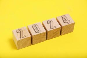 Wooden cubes with numbers 2024 yellow background. photo