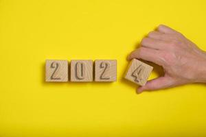 Wooden cubes with numbers 2024 yellow background are made by hand. photo