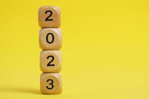 Wooden cubes with numbers 2023 yellow background. photo