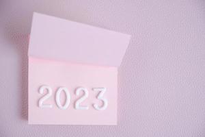 Year 2023 is laid out in white numbers pink sheet.Concept time and new year. photo