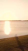 A man taking a picture of the sun reflects on the calm river video