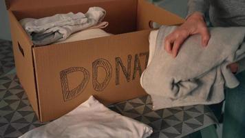 woman puts clothes in box for charity video