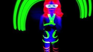 vrouw disco raver meisje poses in uv kostuum met spinnen LED poi lichten video