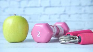 Pink color dumbbell and an apple on the table video