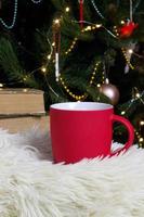 blanco rojo jarra con Navidad árbol en fondo, estera té o café taza con Navidad y nuevo año decoración,horizontal burlarse de arriba con cerámico jarra para caliente bebidas, vacio regalo impresión modelo foto