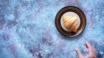 hand pick a fresh baked croissant on plate with copy space video