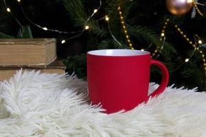 blanco rojo jarra con Navidad árbol en fondo, estera té o café taza con Navidad y nuevo año decoración,horizontal burlarse de arriba con cerámico jarra para caliente bebidas, vacio regalo impresión modelo foto