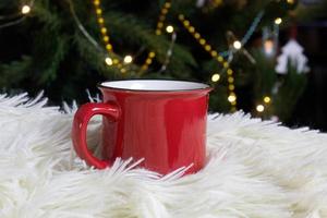 blanco rojo jarra con Navidad árbol en fondo, te o café taza con Navidad y nuevo año decoración,horizontal burlarse de arriba con cerámico jarra para caliente bebidas, vacio regalo impresión modelo foto