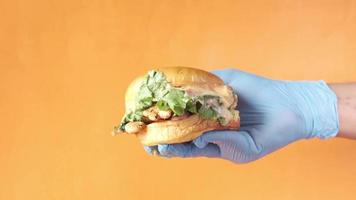 Hand in latex gloves holding beef burger on table close up video