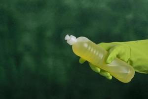 hand with protective glove holding packaging of cleaning products used for home hygiene photo