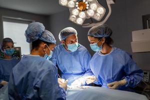 Diverse Team of Professional surgeon, Assistants and Nurses Performing Invasive Surgery on a Patient in the Hospital Operating Room. Surgeons Talk and Use Instruments. Real Modern Hospital. photo