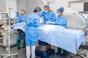 Group of medical team urgently doing surgical operation and helping patient in theater at hospital. Medical team performing surgical operation in a bright modern operating room photo