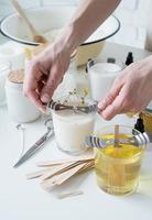 closeup of woman setting the wooden wick into handmade candle photo