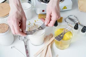 closeup of woman setting the wooden wick into handmade candle photo