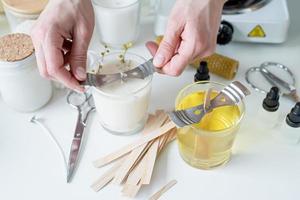 closeup of woman setting the wooden wick into handmade candle photo