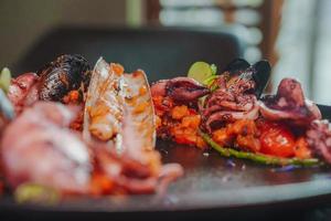 Grilled octopus with calmars,  salad and lemon on plate. photo