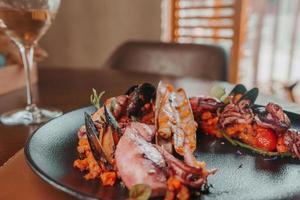 Grilled octopus with calmars,  salad and lemon on plate. photo