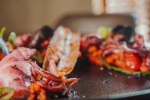 Grilled octopus with calmars,  salad and lemon on plate. photo