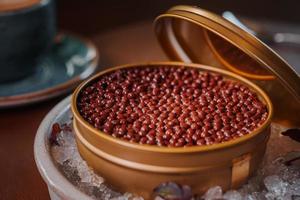 Black caviar in can placed on a plate with ice. photo