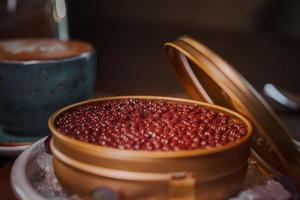 Black caviar in can placed on a plate with ice. photo