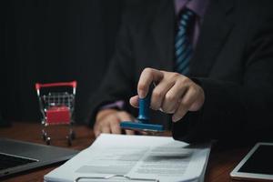 Man hand stamping approval signing on document or paperwork contract at desk. photo
