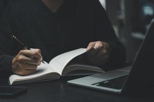 man hands with pen writing on notebook in the office.learning, education and work.writes goals, plans, make to do and wish list on desk. photo
